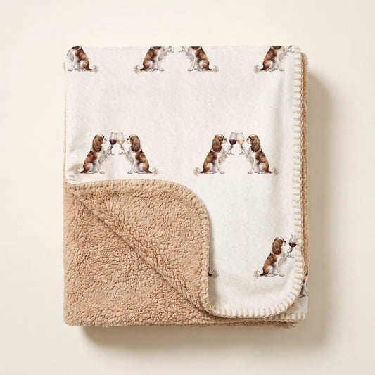 Top-down product photo of the Happy Hour Cavalier King Charles Spaniel sherpa blanket folded on a cream background